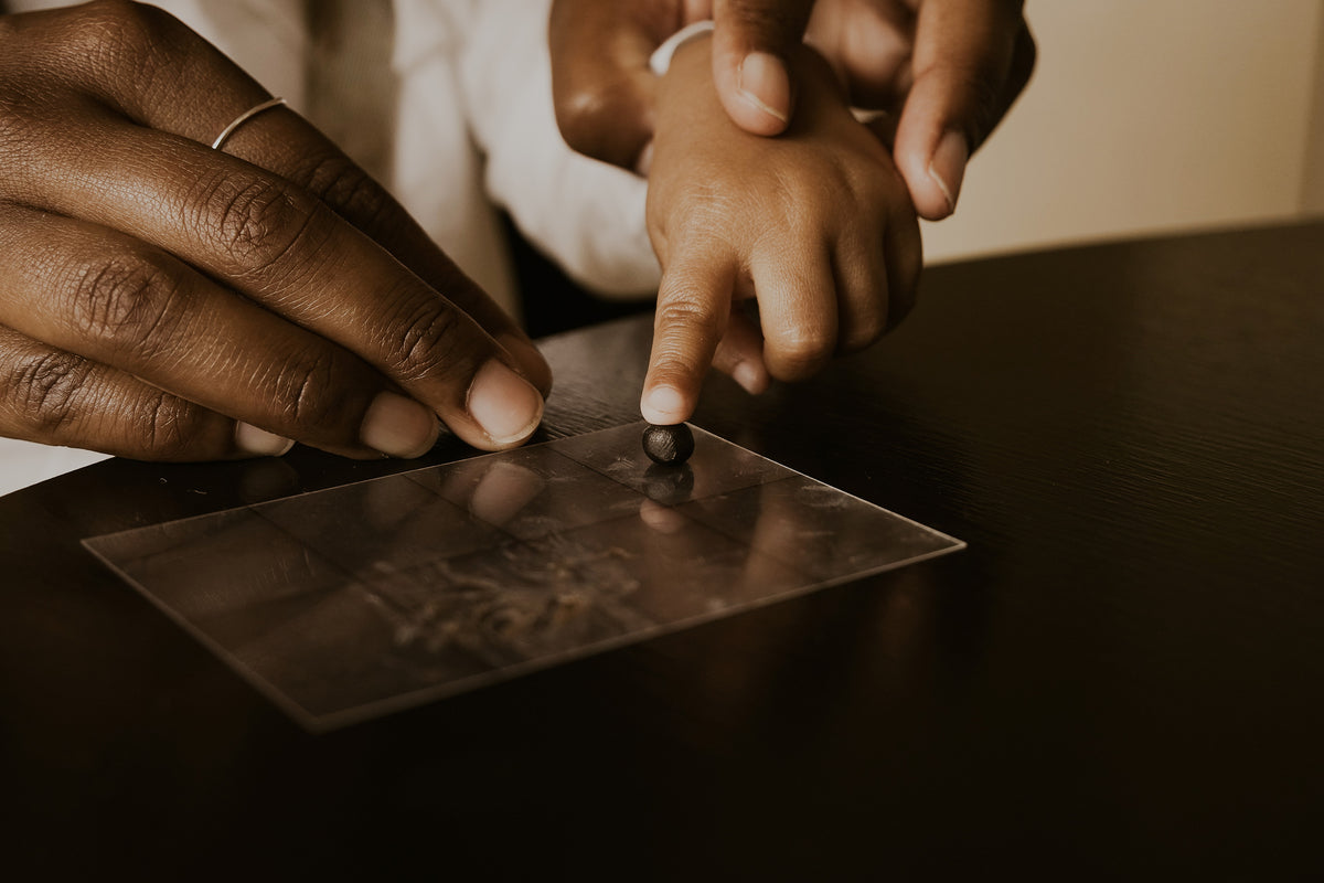 Hands press a fingerprint into impression wax